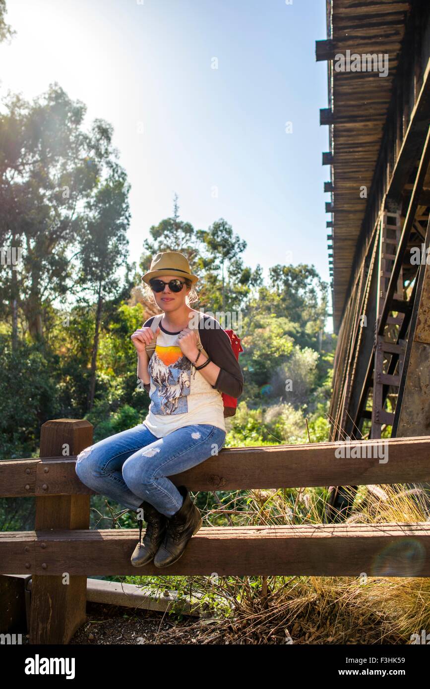 Woman sitting on log fence, El Capitan, California, USA Stock Photo