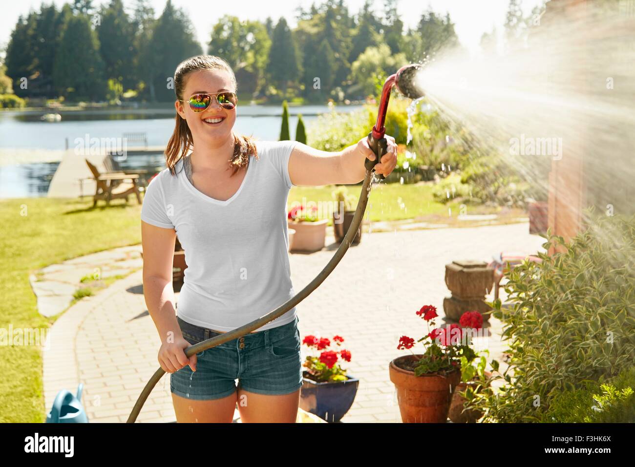 Girl watering plants at lake house, Seattle, Washington, USA Stock Photo