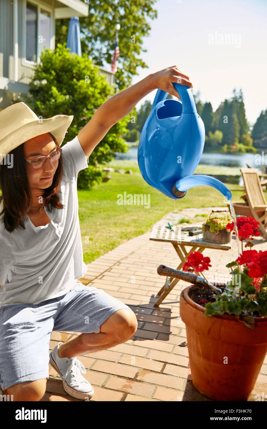 Man watering plants at lake house, Seattle, Washington, USA Stock Photo