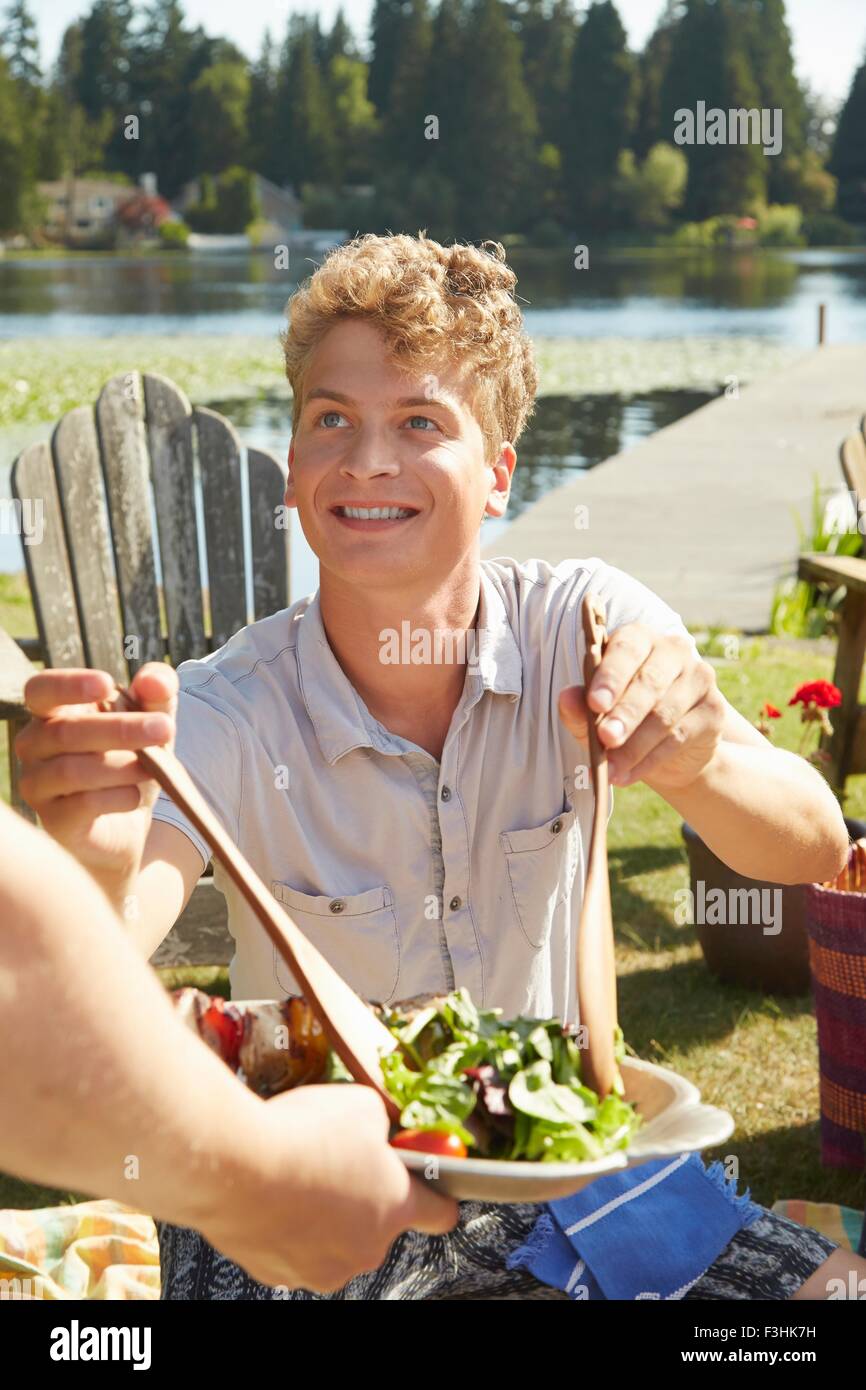 Man helping himself to salad at lake party, Seattle, Washington, USA Stock Photo