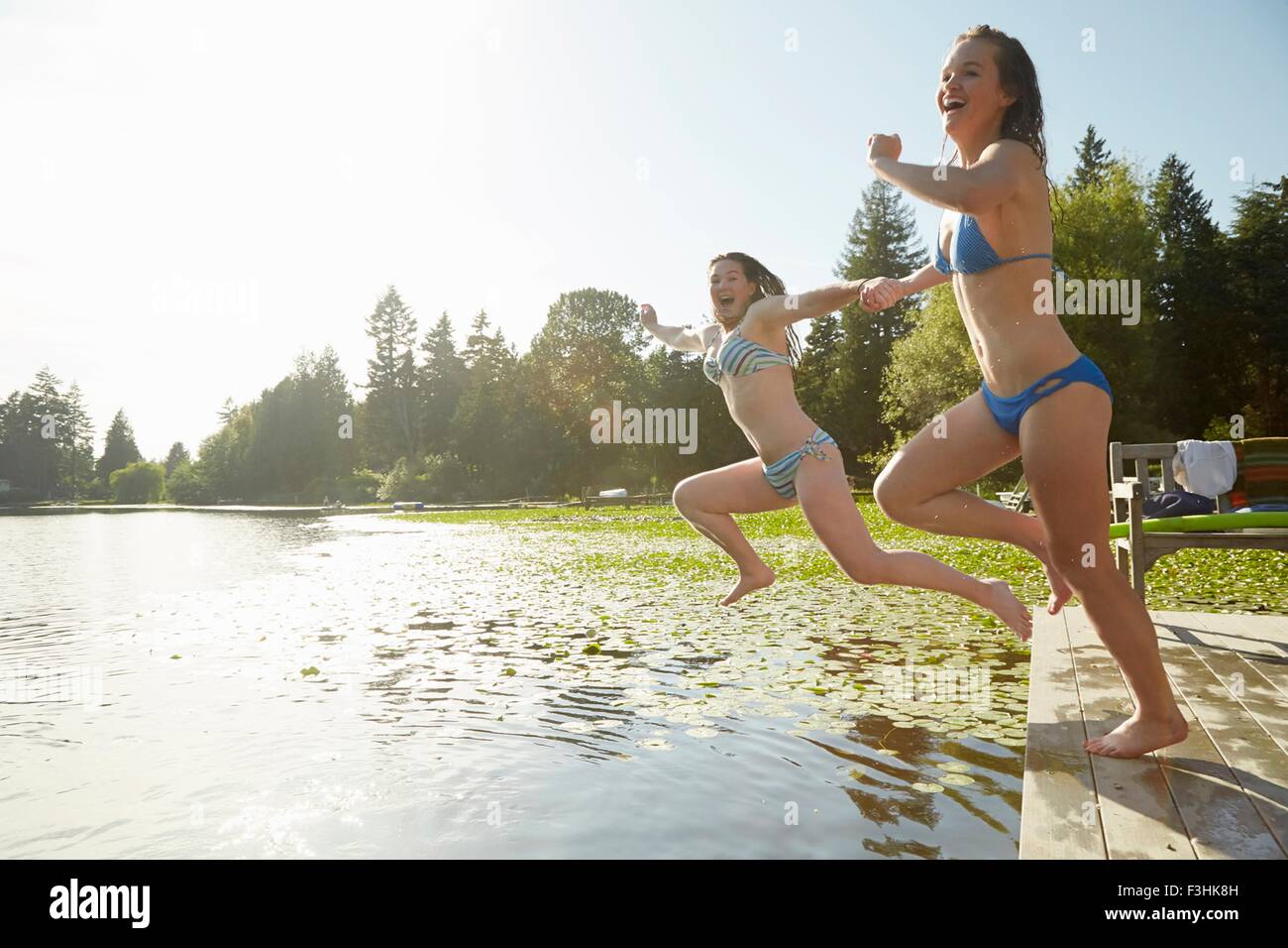 Girls in bikini jumping into lake, Seattle, Washington, USA Stock Photo