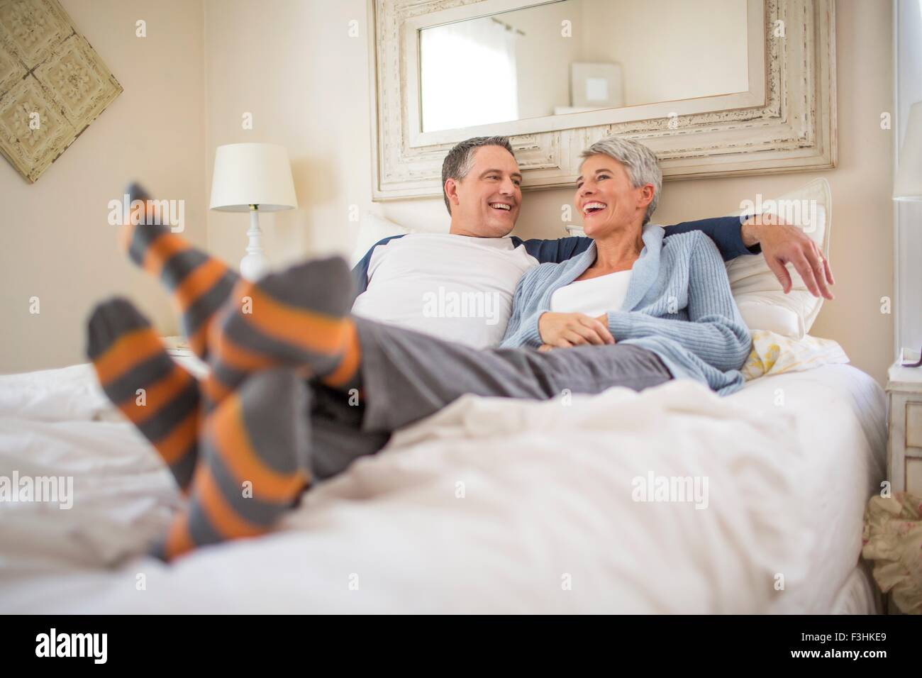 Mature couple chatting and relaxing on bed Stock Photo