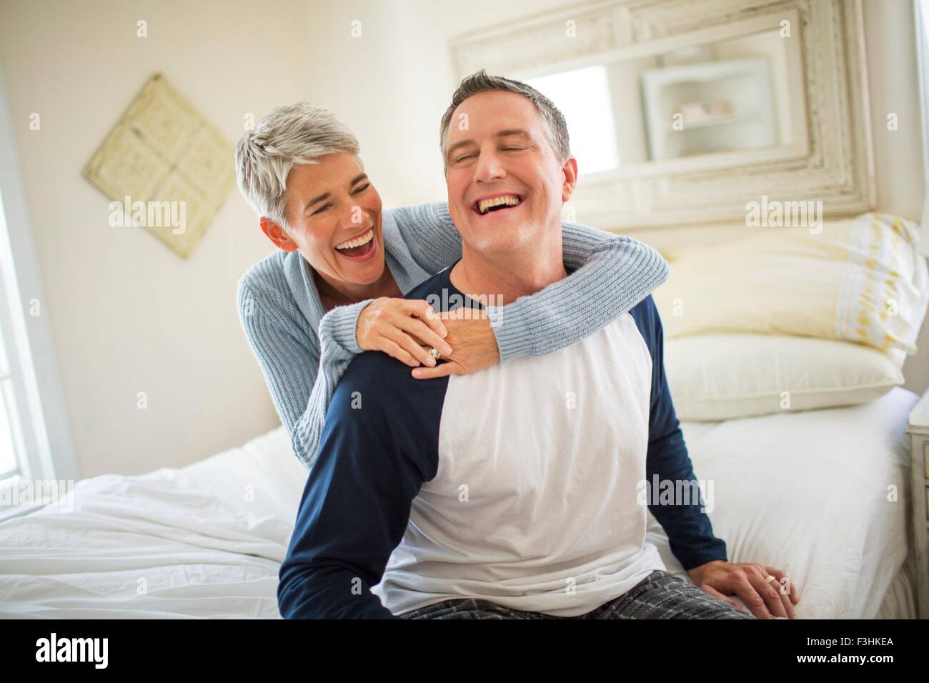 Mature couple laughing and fooling around on bed Stock Photo