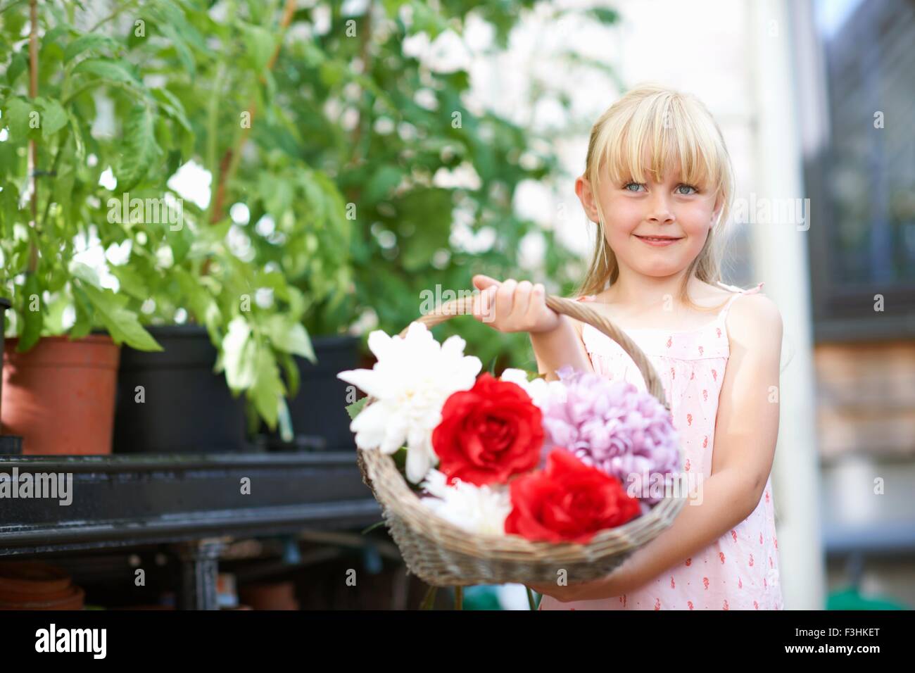 Cute girl holding fresh flower basket in greenhouse Stock Photo