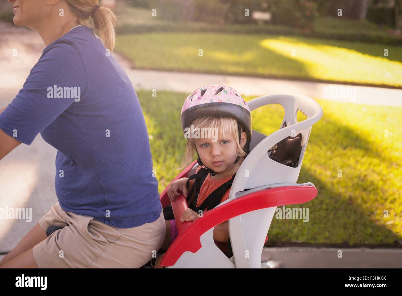 Mature woman on bicycle with daughter sitting in child's seat behind her Stock Photo