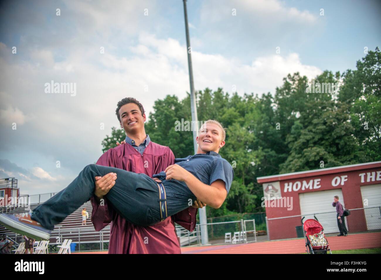 Young man lifting male friend at graduation ceremony Stock Photo