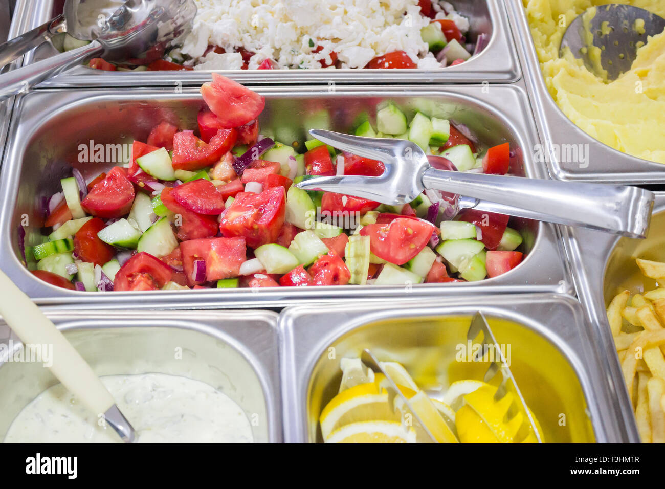 Salad bar in a cafeteria with fresh mixed salads and dressings Stock Photo