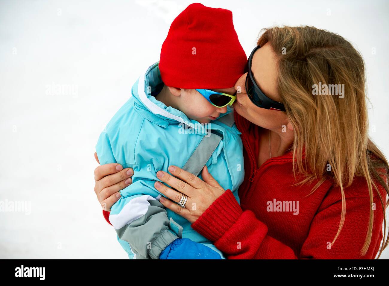 Skiing mother kissing toddler son on forehead Stock Photo