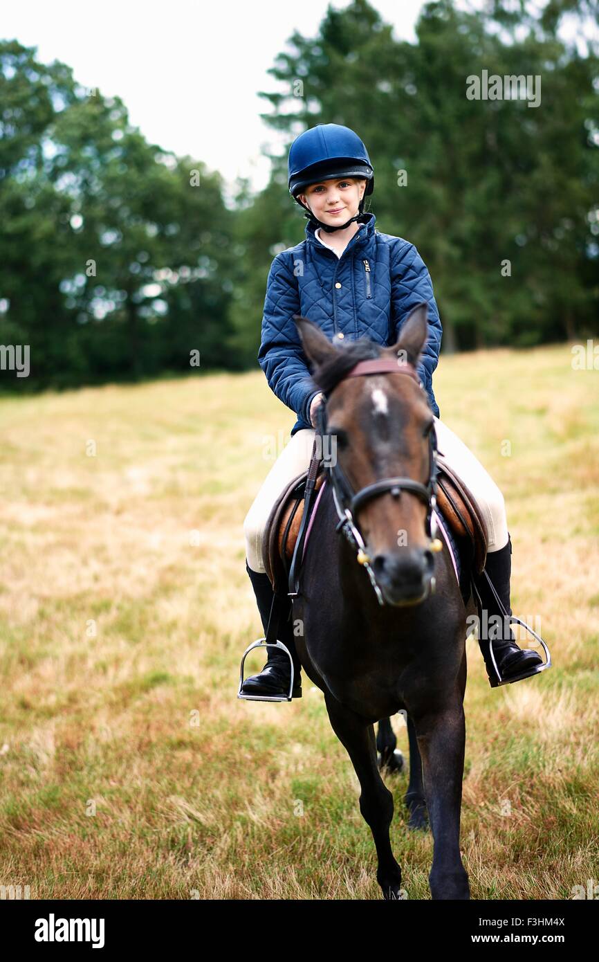 Portrait of girl horseback riding in field Stock Photo
