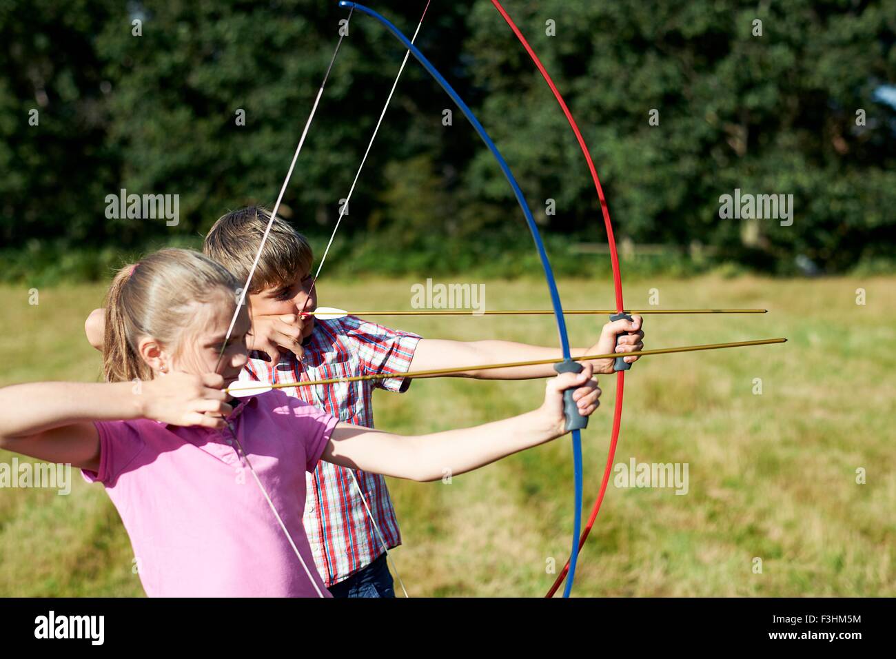 Girl and teenage brother practicing archery Stock Photo