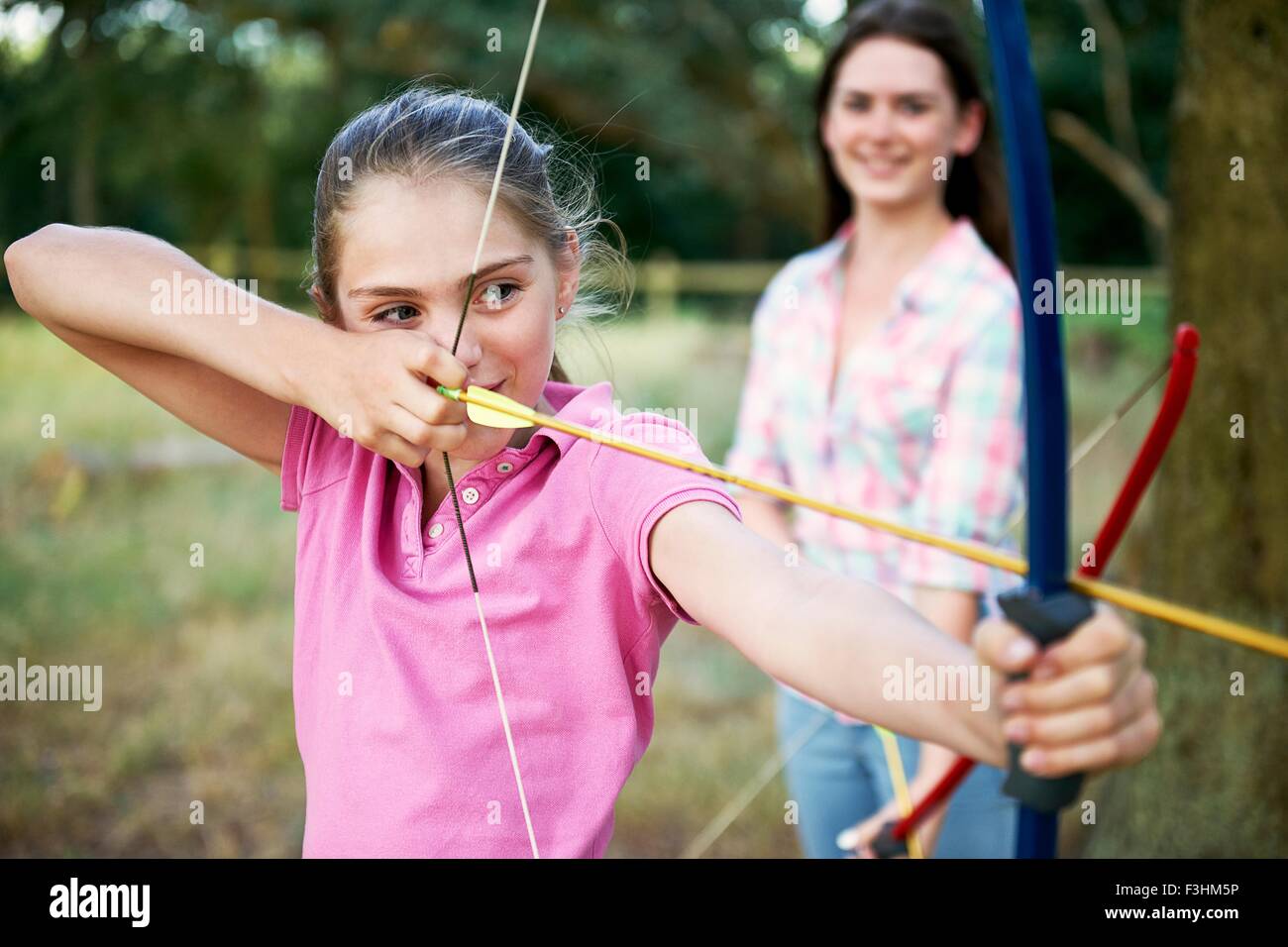 Girl practicing archery aiming with bow and arrow Stock Photo