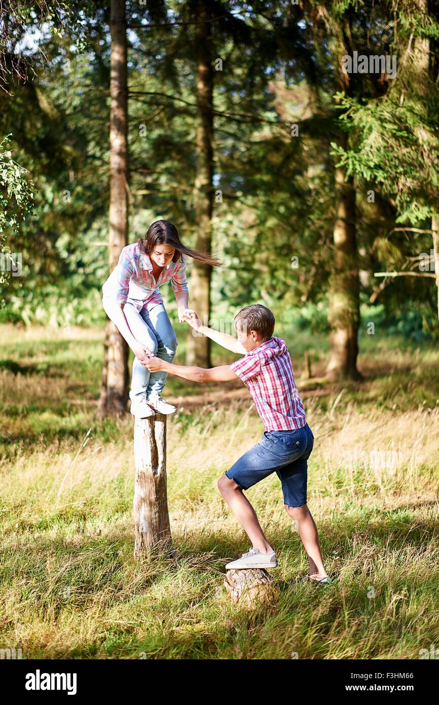 Teenage brother and sister balancing on top of fence post Stock Photo