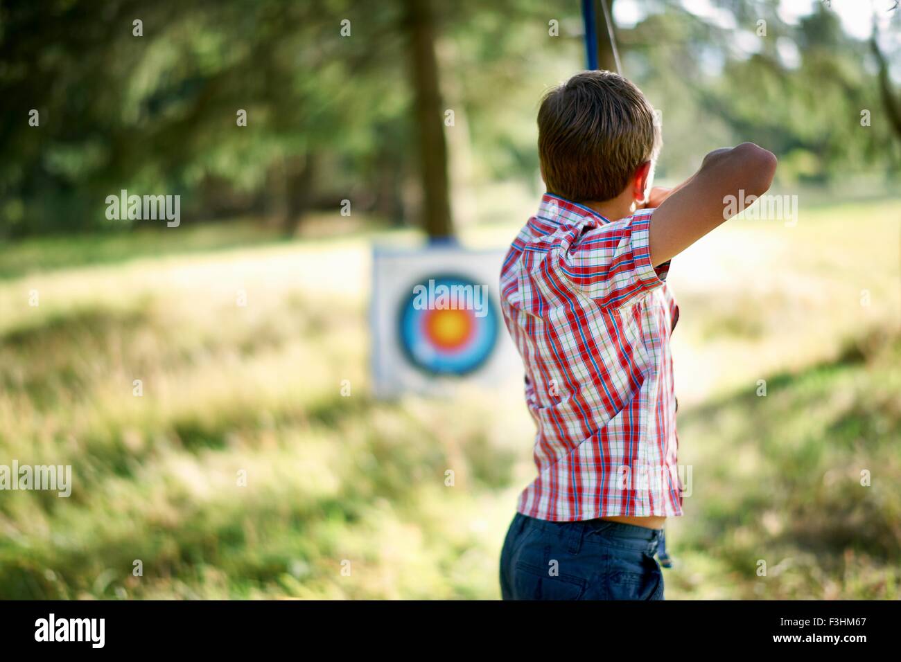 Rear view of teenage boy practicing archery with target Stock Photo