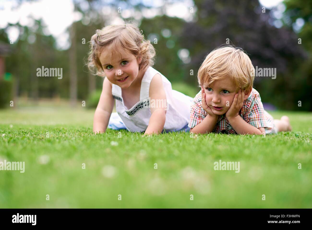 Surface level of boy and girl lying on grass Stock Photo