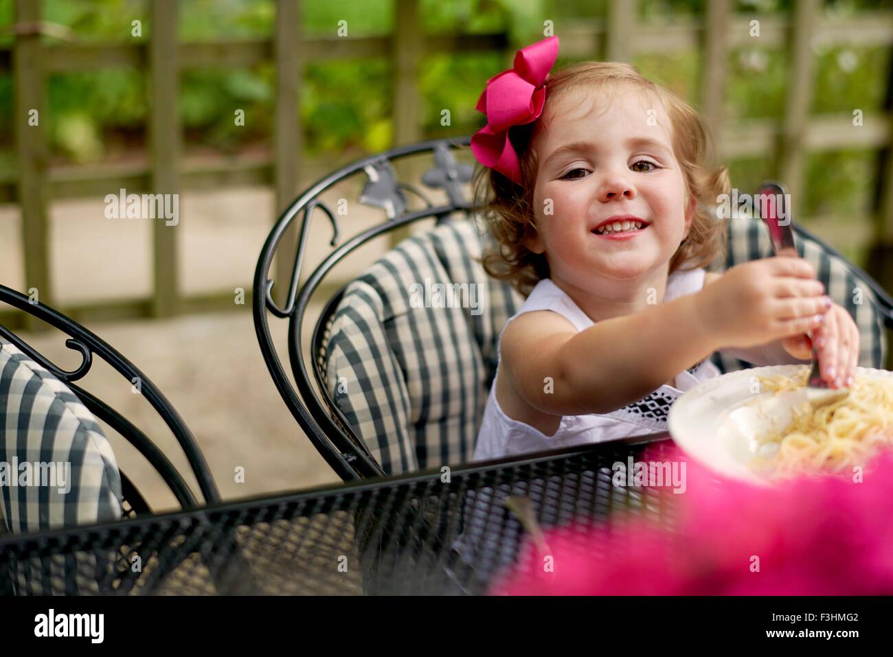Girl dining at garden table looking at camera smiling Stock Photo