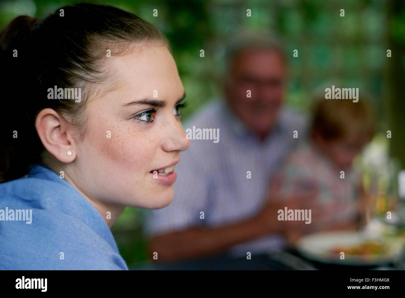Side view of teenage girls head and shoulders looking away smiling Stock Photo