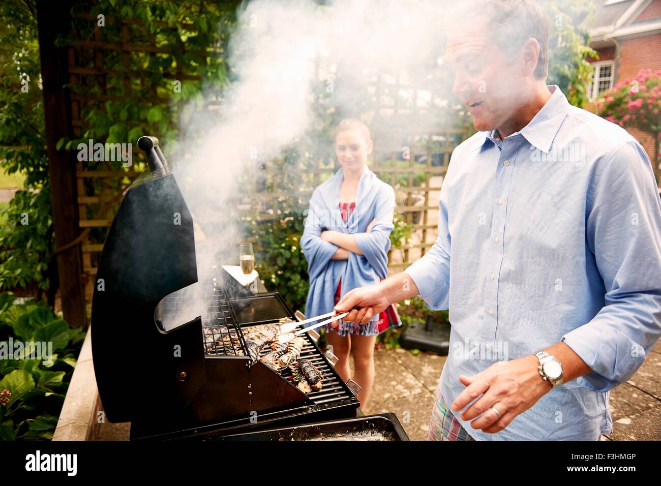 Daughter watching father cook sea food on barbecue Stock Photo