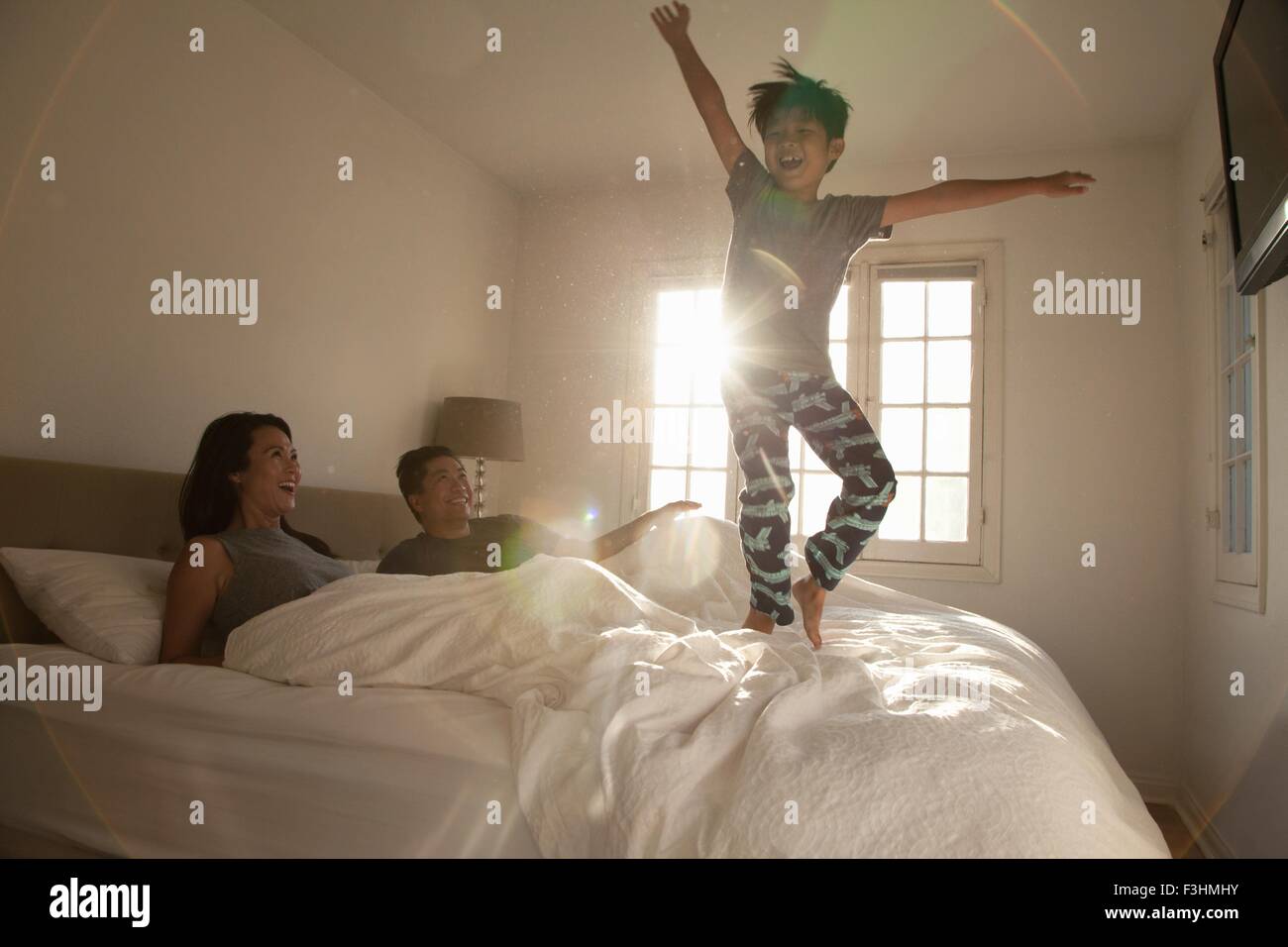 Boy jumping on parents bed Stock Photo Alamy