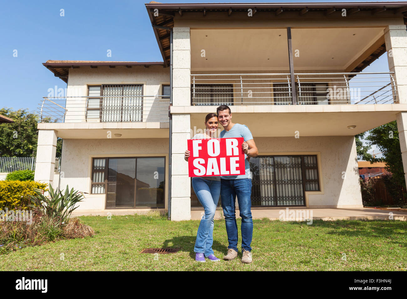 portrait of lovely couple holding for sale sign in front of house Stock ...
