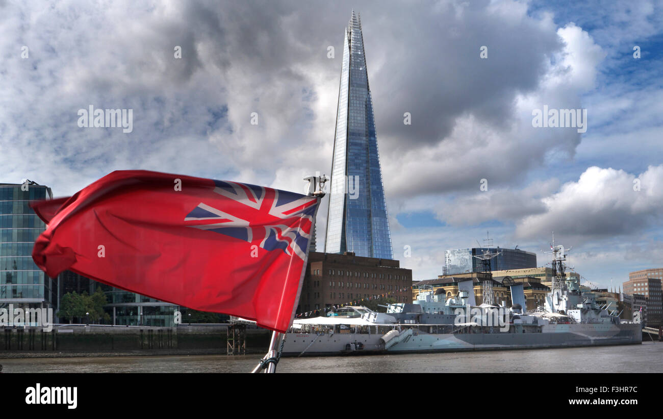 View to South Bank from Thames Clipper river boat with 'Red Ensign' flag, HMS Belfast, The Shard and More London Place SE1 Stock Photo