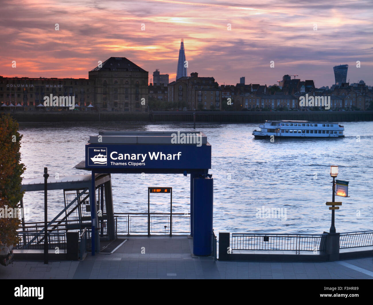 Sunset at Canary Wharf River Boat jetty with pleasure boat London Shard and 'Walkie Talkie' building in background London E14 Stock Photo