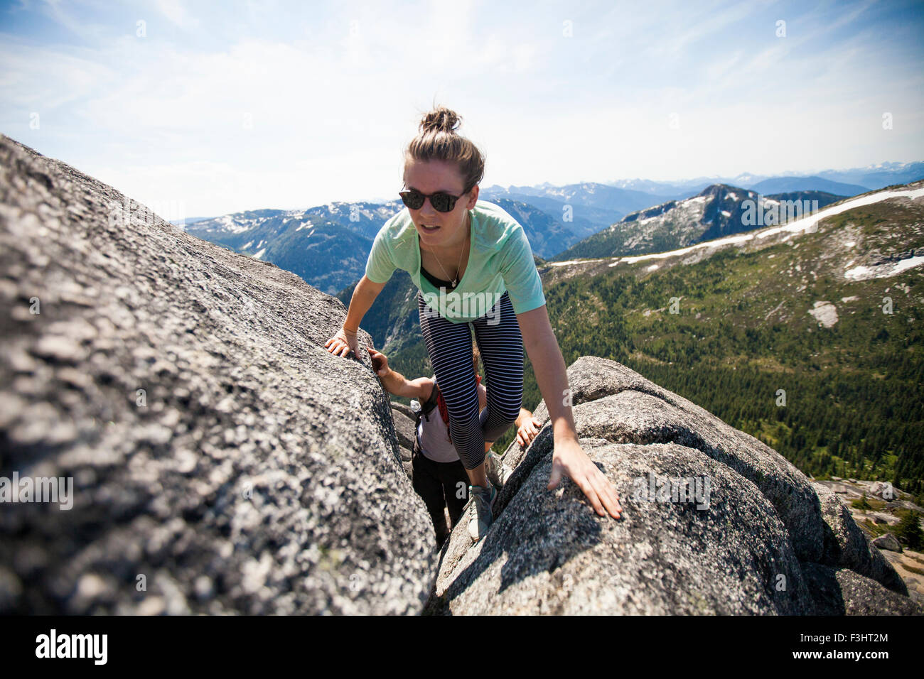 A man and woman scrambling up granite rock Stock Photo - Alamy