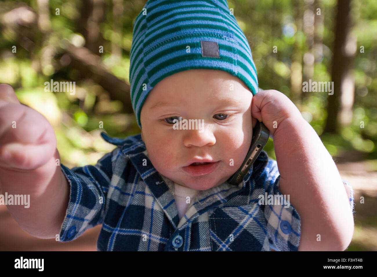 A young boy pretends to talk on a smartphone. Stock Photo