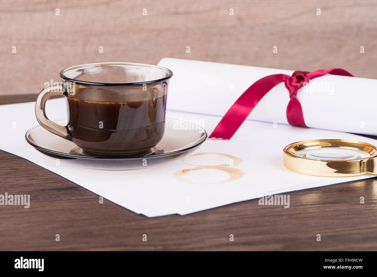 Coffee cup, paper sheets and detective hat on old Wooden table. Stock Photo