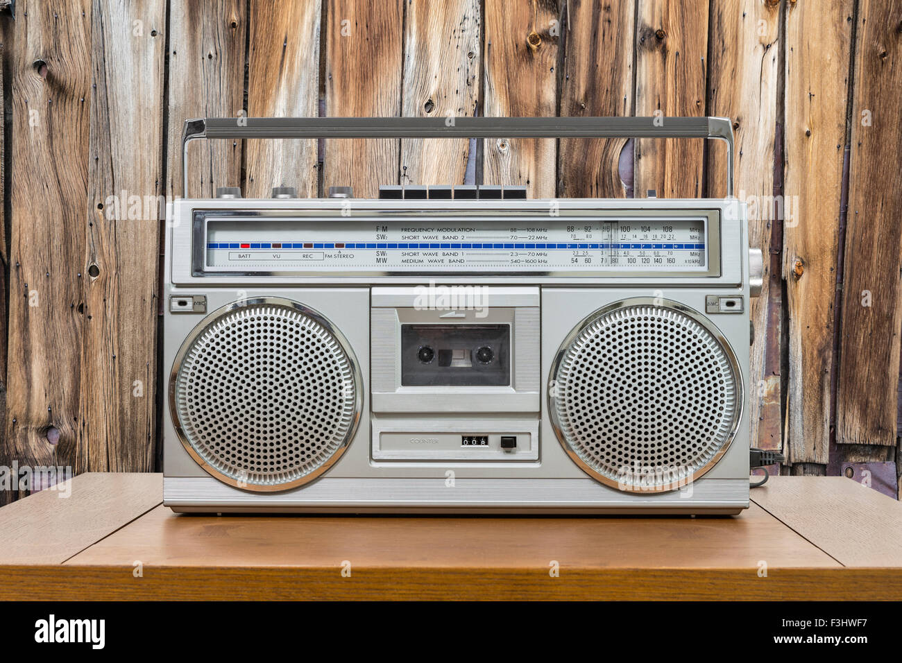 Vintage boombox on wood table with rustic cabin wood wall. Stock Photo