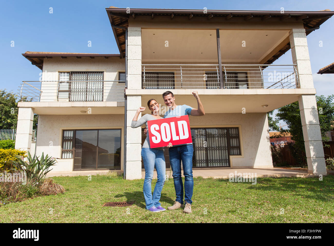 happy couple standing outside their house and holding sold sign Stock ...