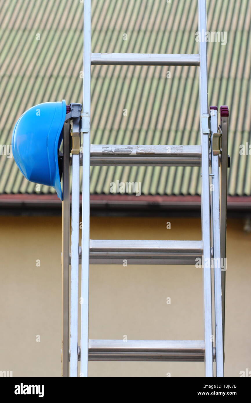 Protective blue helmet on aluminum ladder, concept of security and protection at work Stock Photo