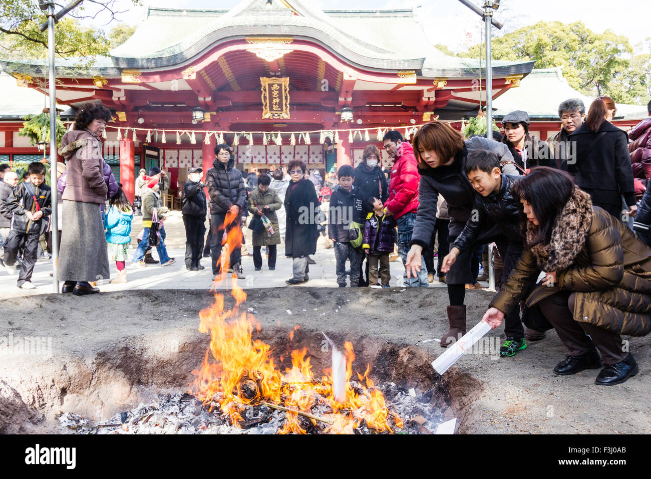 Japan, new year's day. Crowds of people at Nishinomiya shrine, praying and throwing previous years good luck charms, engimono, into large bonfire. Stock Photo