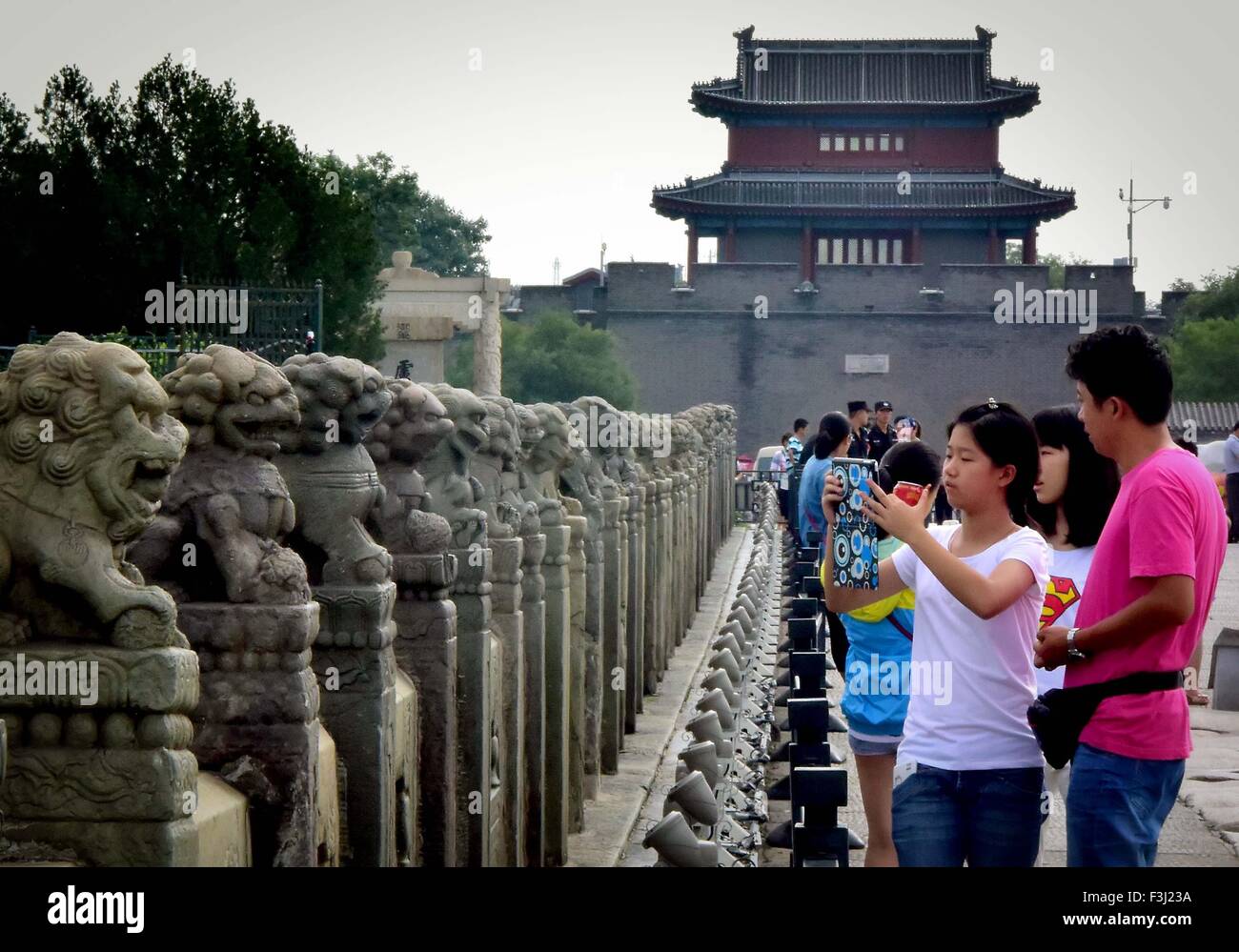 Beijing, China. 26th Aug, 2015. Tourists take photos on the Lugou Bridge across the Yongding River in Beijing, capital of China, Aug. 26, 2015. The Lugou Bridge was originally built in 1189 during the Jin Dynasty and was reconstructed and the Qing Dynasty (1644-1911). The bridge is 266.5 meters long and 7.5 meters wide, with 11 arches. And there are altogether 485 stone lions carved on the columns. © Wang Song/Xinhua/Alamy Live News Stock Photo