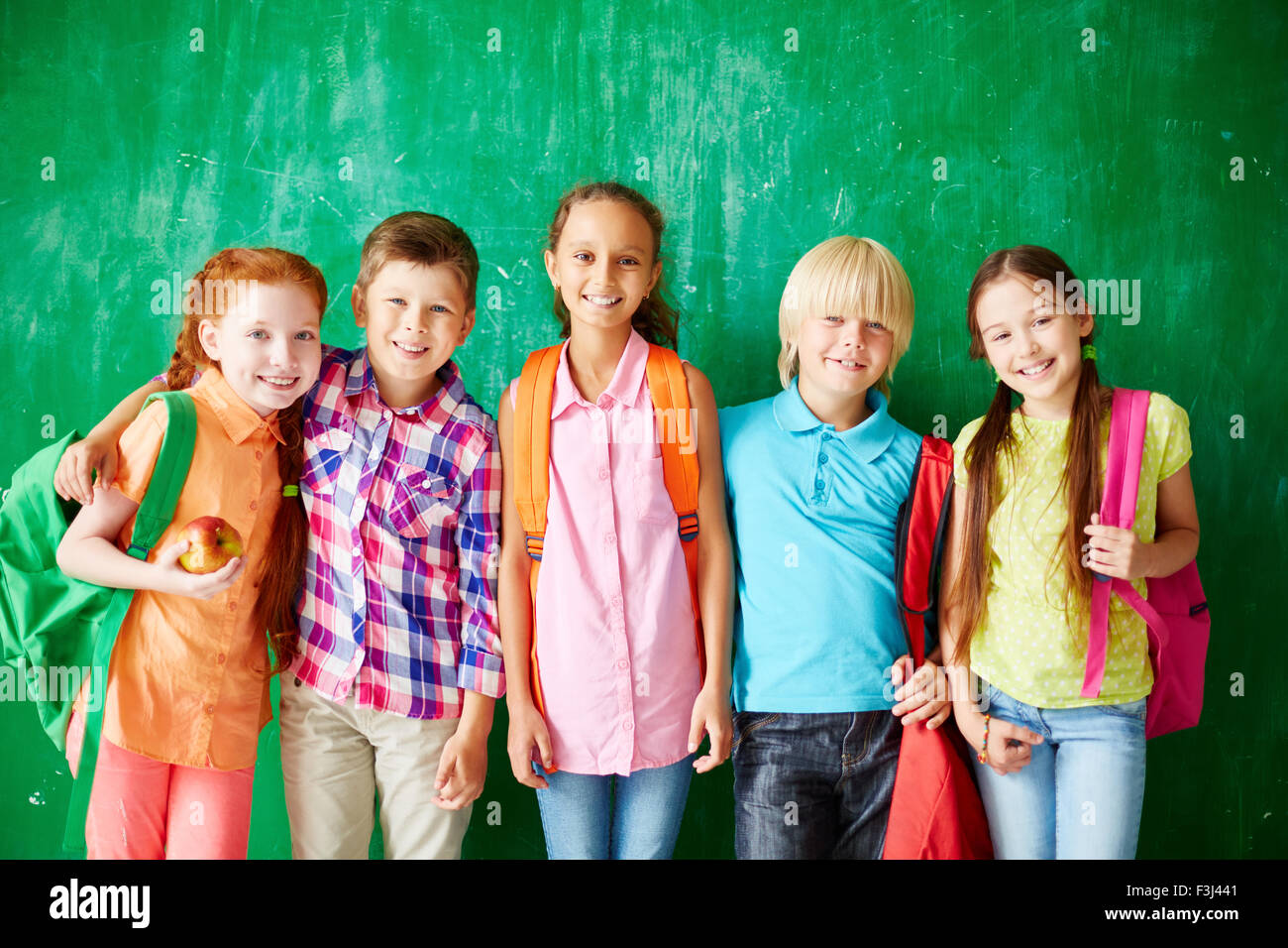 Happy kids with backpacks standing in row along school blackboard Stock ...