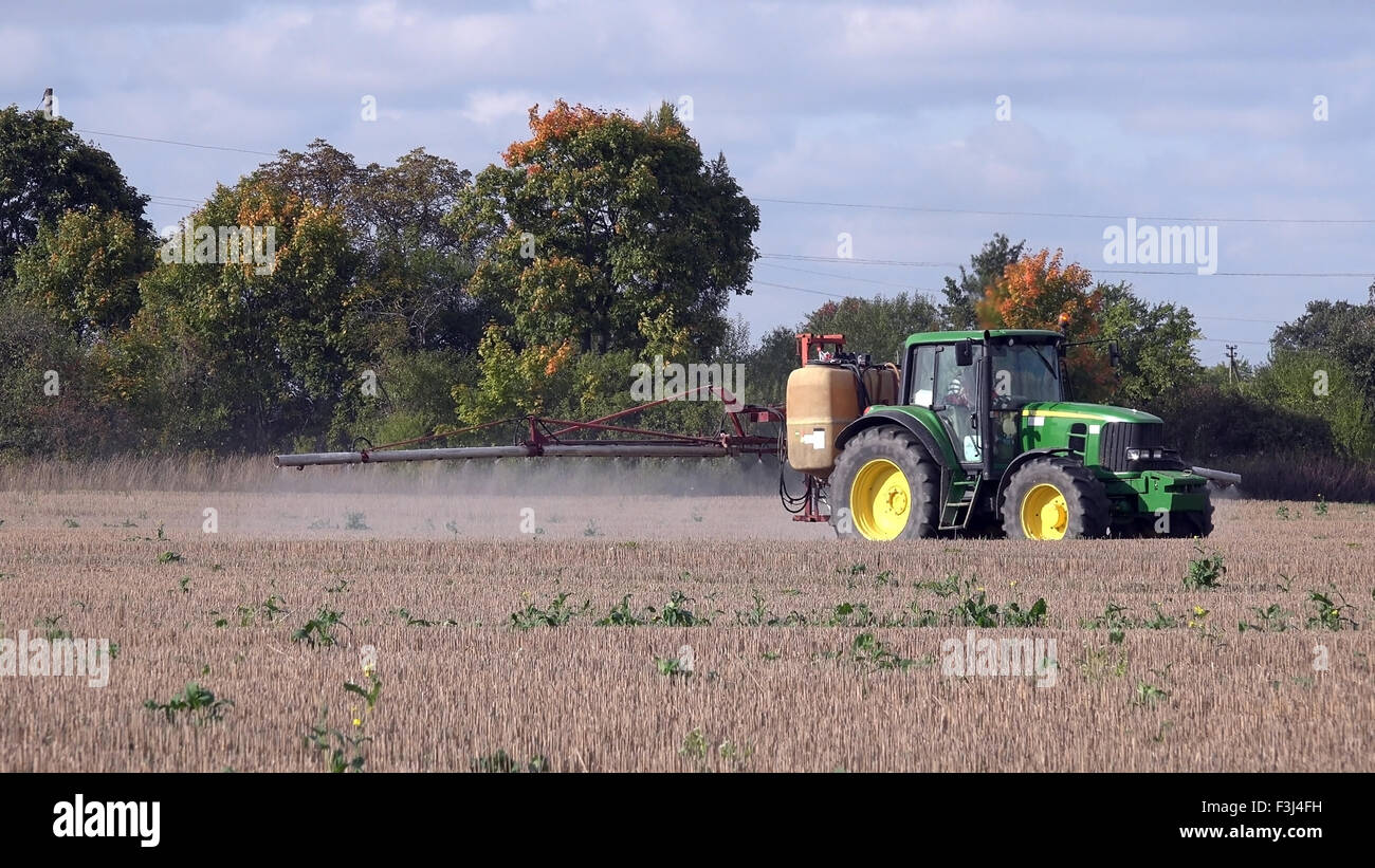 Tractor spraying stubble field with herbicide chemicals in autumn. Farmer with modern vehicle kill weeds in agriculture field be Stock Photo