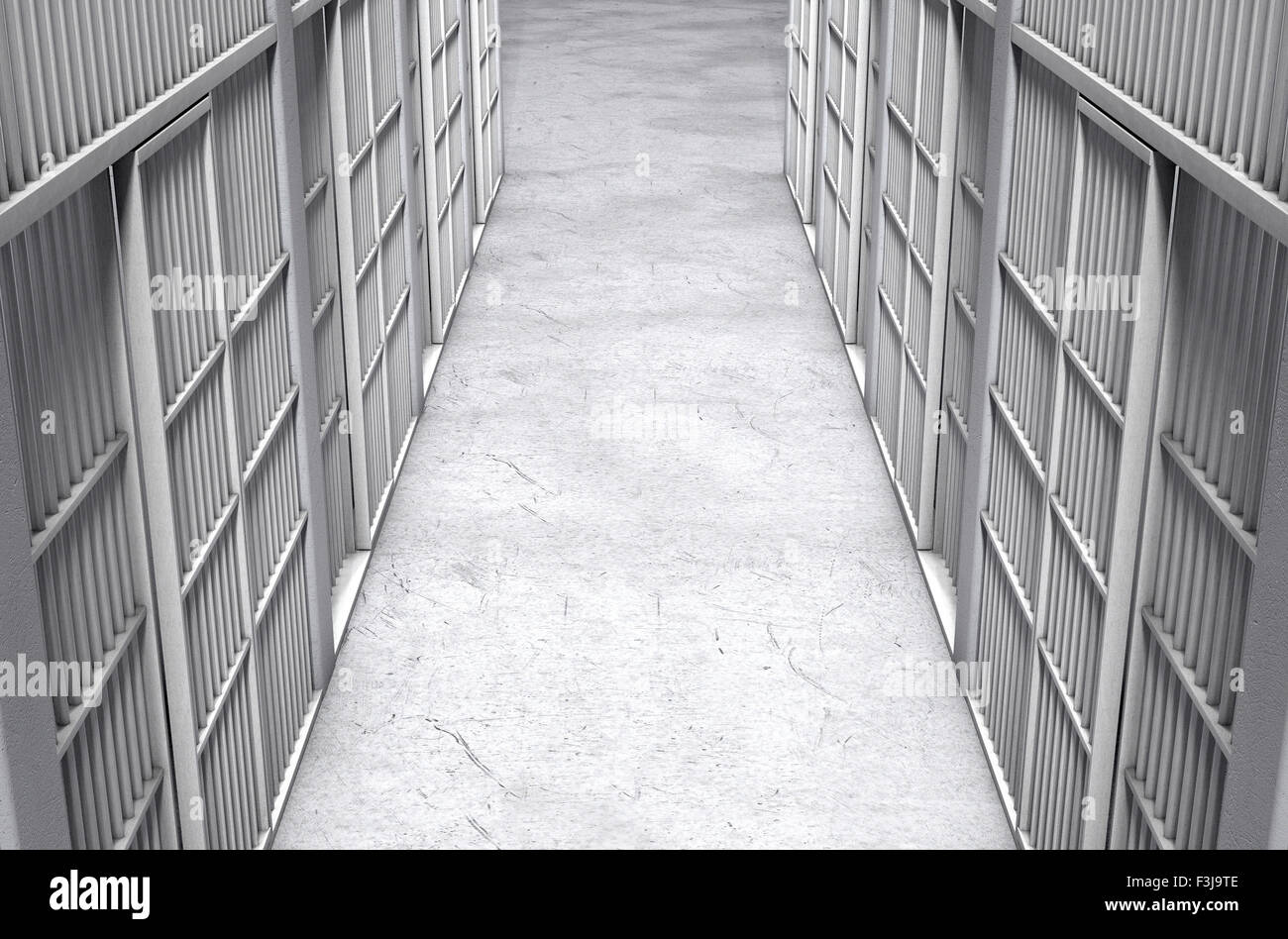 A direct top view of a row of closed jail cells between a concrete aisle lit by a single dramatic spotlight Stock Photo