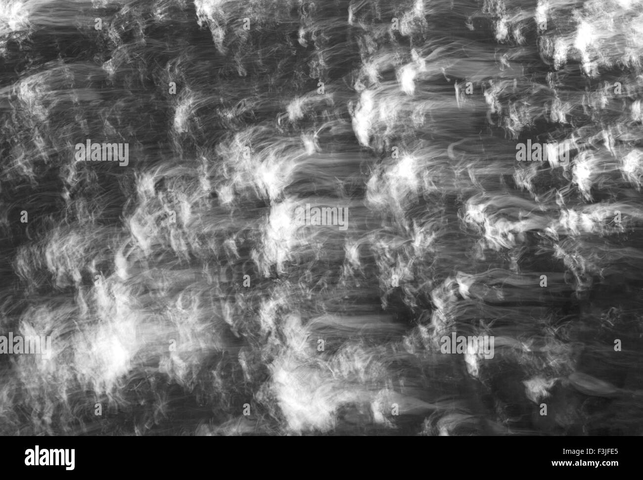 An Intentional Camera Movement Study of water cascading along the River Dove in Derbyshire in Black and White Stock Photo