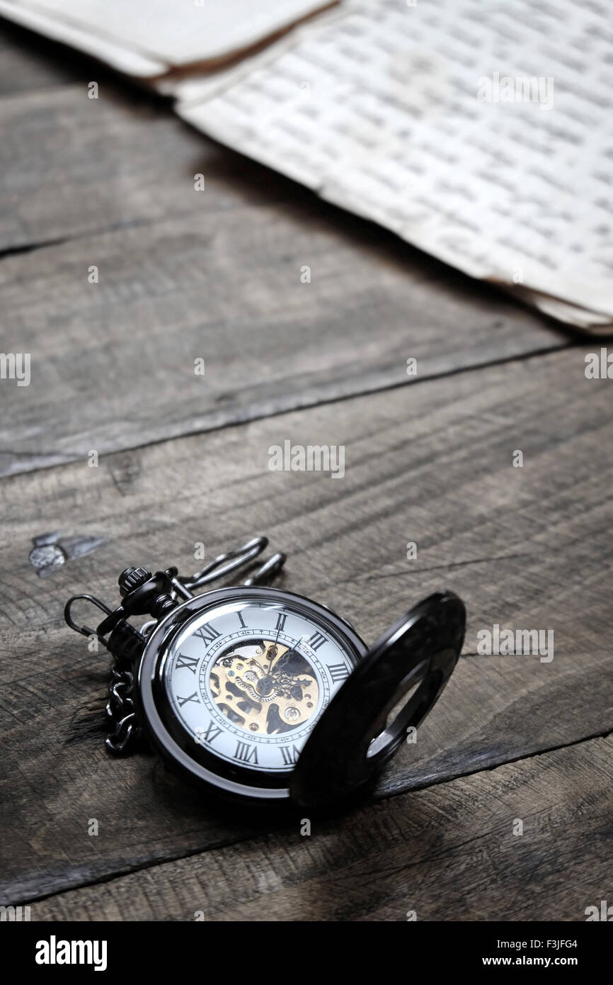 Old vintage pocket watch lying on wooden background, close up Stock Photo