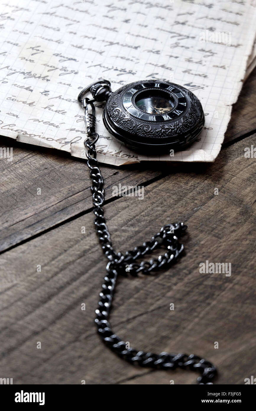 Old vintage pocket watch lying on wooden background, close up Stock Photo