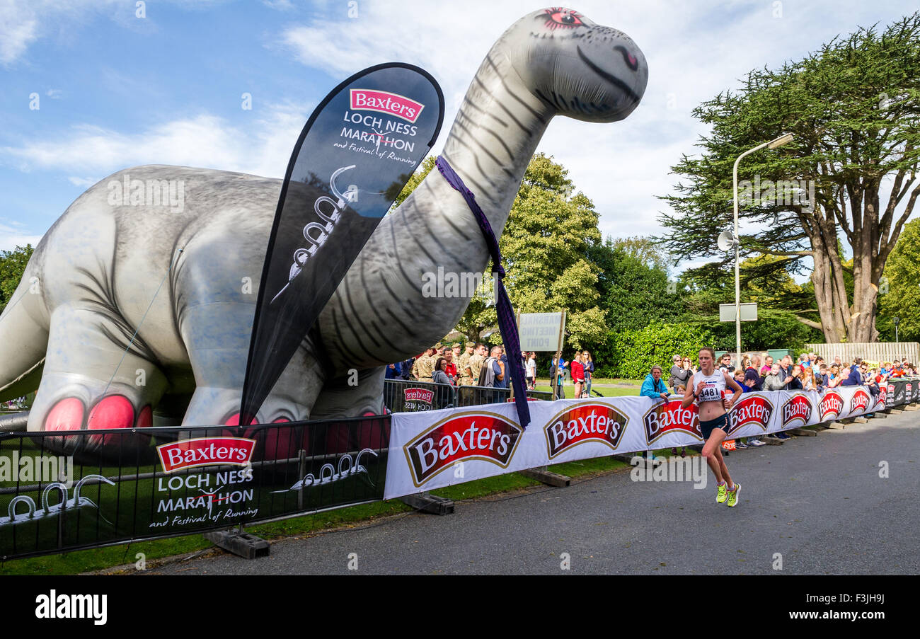 Female runner finishing the Baxters Loch Ness Marathon in Inverness pass a large blow-up model of the Loch Ness Monster Stock Photo