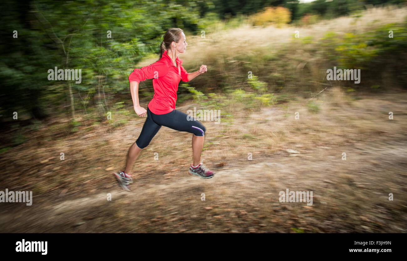 Young woman running outdoors in a forest, going fast (motion blurred ...