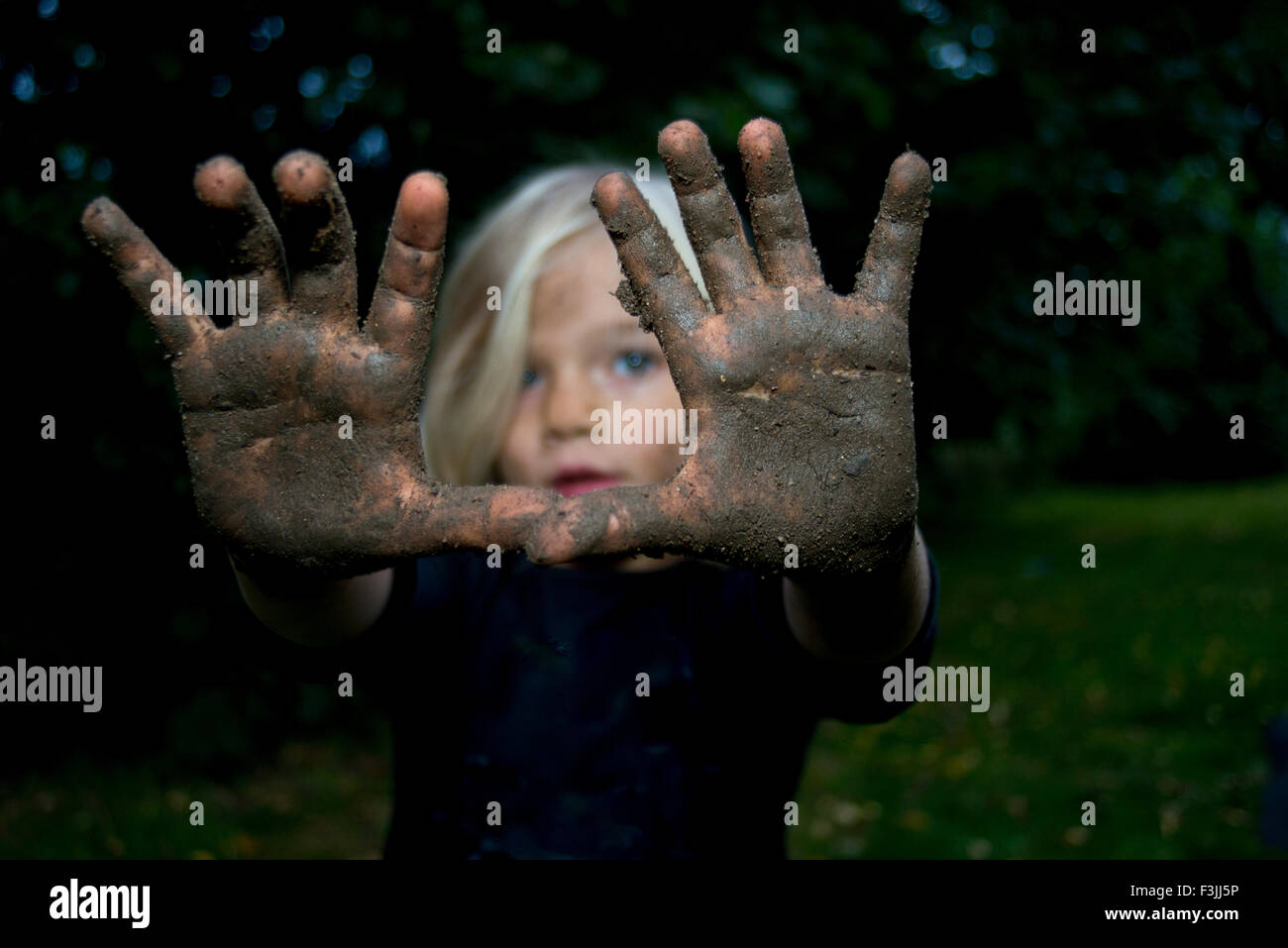 Portrait of little child blond girl showing hands full of dirt Stock Photo