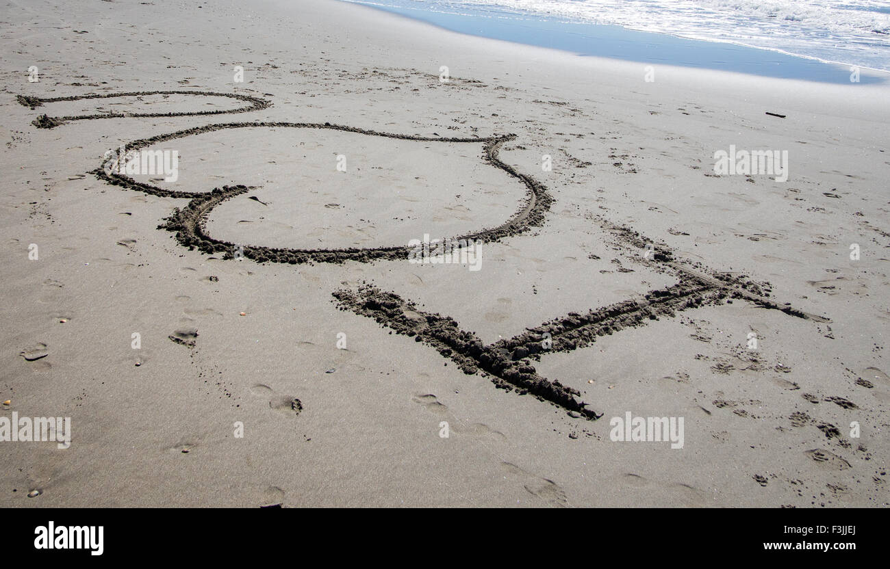 I 'heart' u written in the sand on a beach in France. A wave breaks in the top right hand corner.  The heart symbolises love. Stock Photo