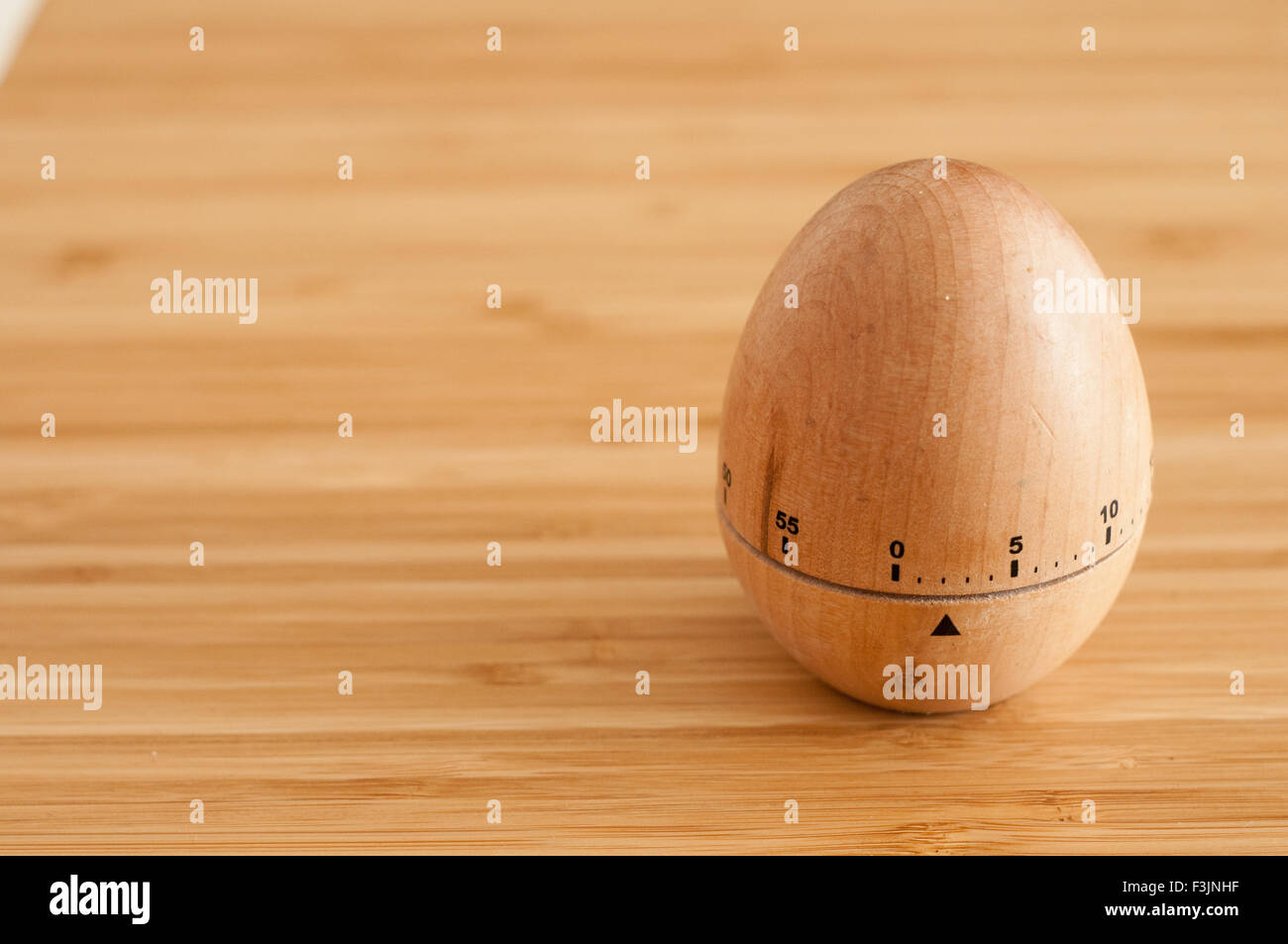 Egg timer on a wooden surface in natural light Stock Photo