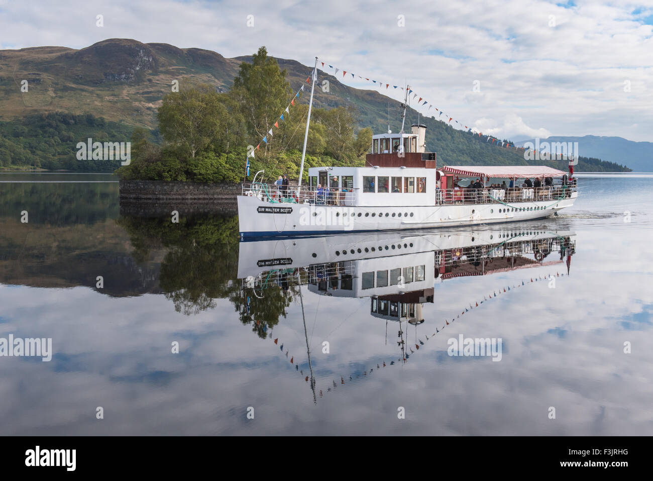 The steamship Sir Walter Scott arriving at the pier at Stronachlachar on Loch Katrine, with perfect reflections in the water. Stock Photo