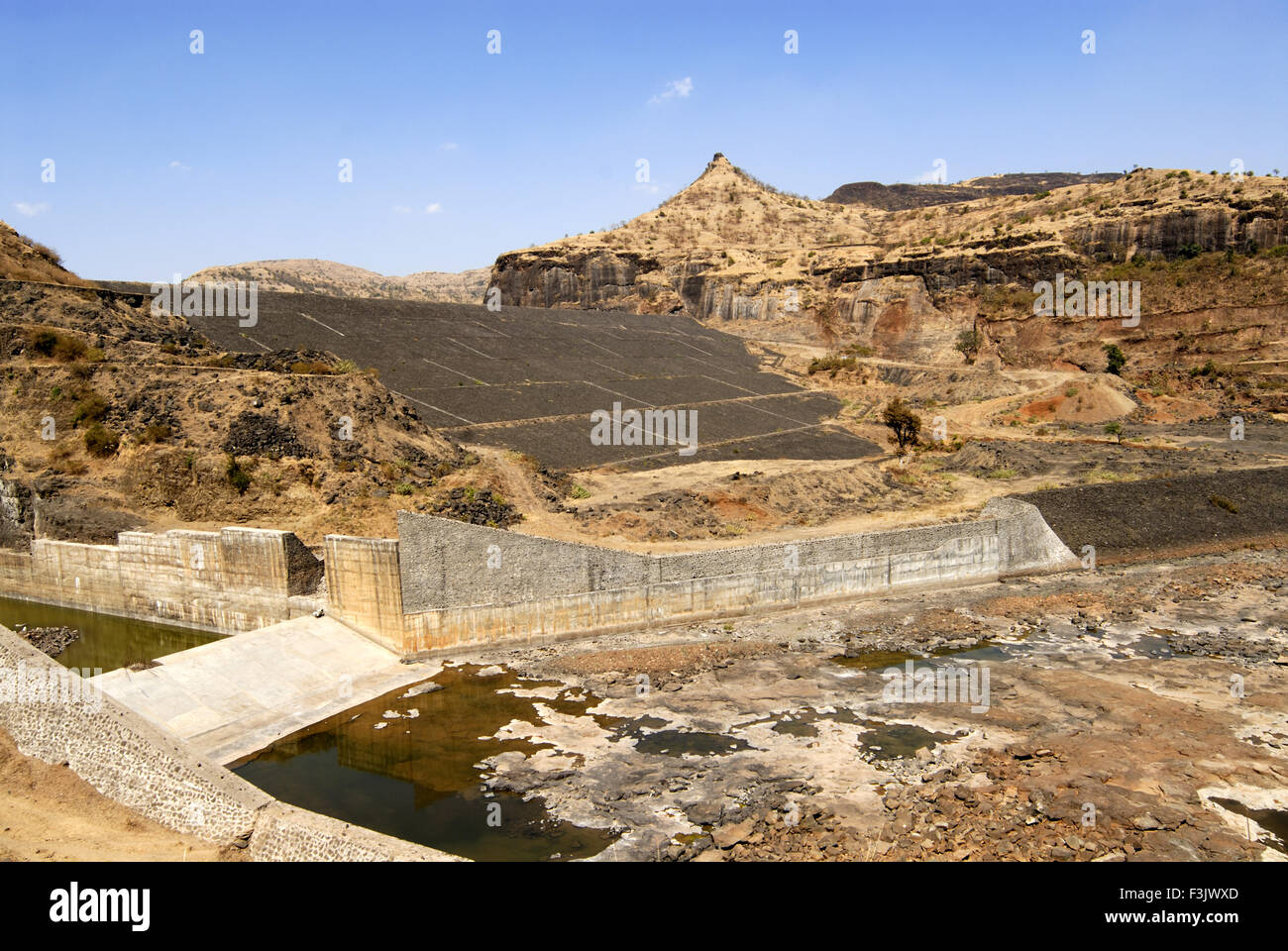 Earthen dam with stone pitching constructed between rock mountains Chilhewadi village Otur Junnar Pune maharashtra india asia Stock Photo