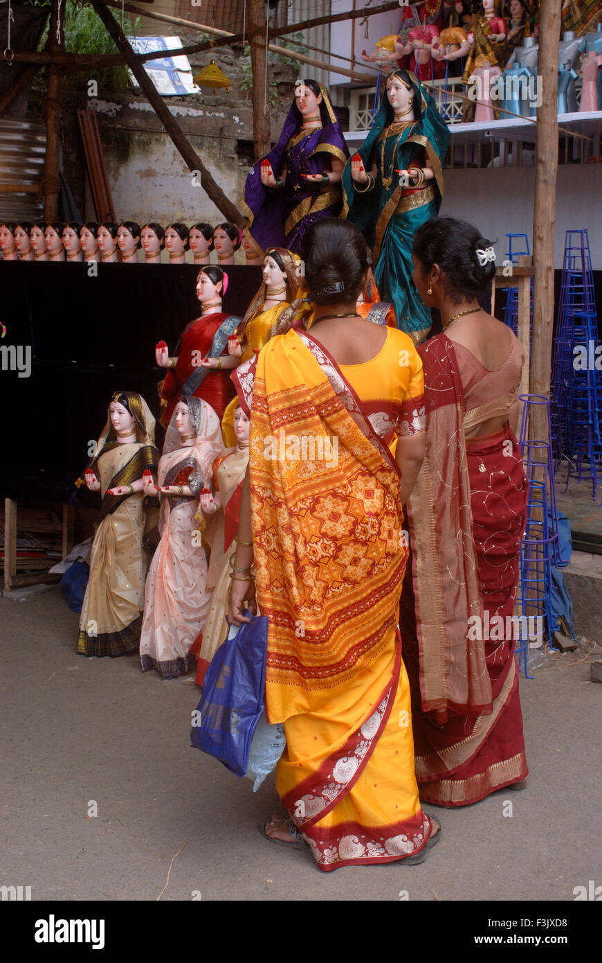 Women buying Idols of Goddess Gauri wearing colorful saris Ganapati festival Pune maharashtra india Stock Photo