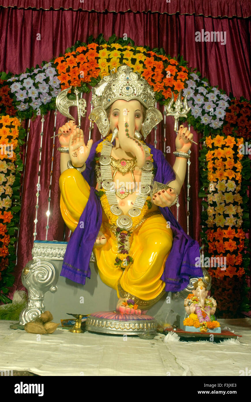 idol of Lord Ganesh with simple decoration of artificial flowers ...