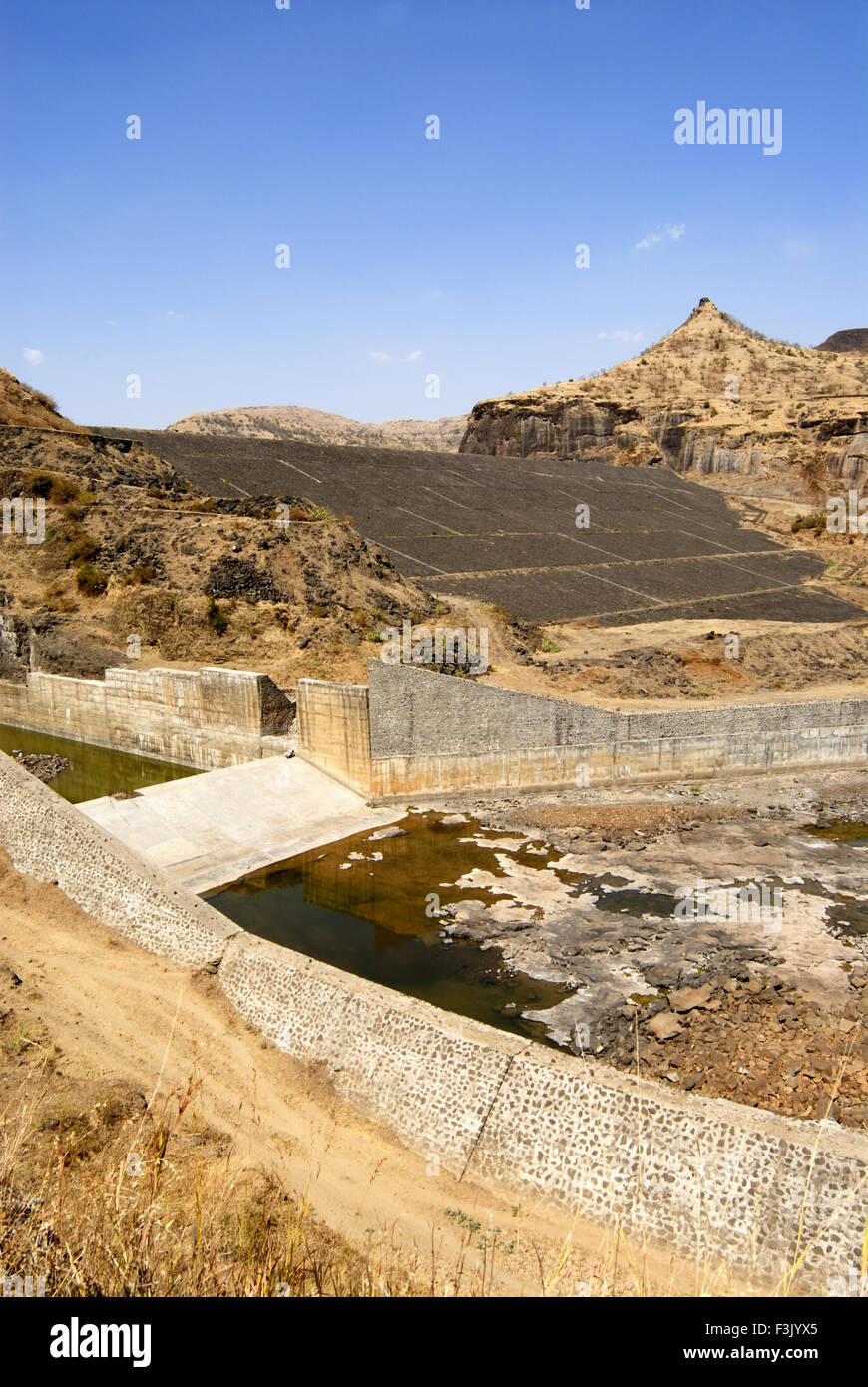 Earthen dam with stone pitching constructed between rock mountains at Chilhewadi near village Otur Junnar Pune maharashtra india asia Stock Photo