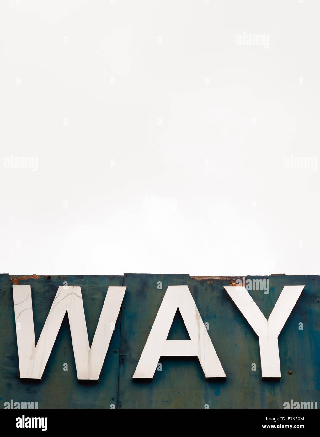 An old wooden signboard pictured against an overcast sky. The sign says 'WAY'. Stock Photo